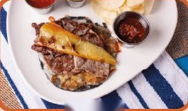 Gaonera de ribeye con costra de queso y chile asado, acompañada de salsas taqueras